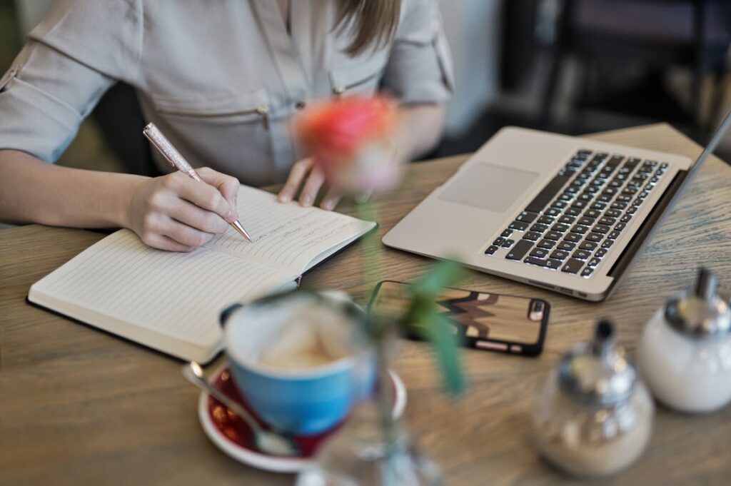 Frau schreibt in Content-Marketing Notizbuch auf Schreibtisch.