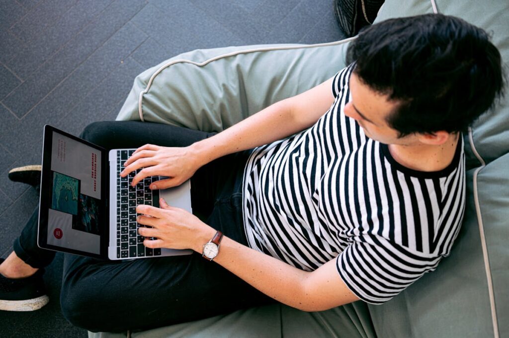 Mann mit Laptop auf Sofa.