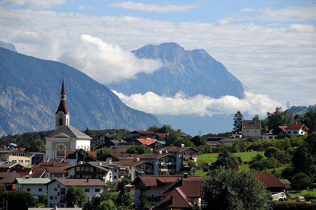 Dorf in Österreich vor Bergkulisse.